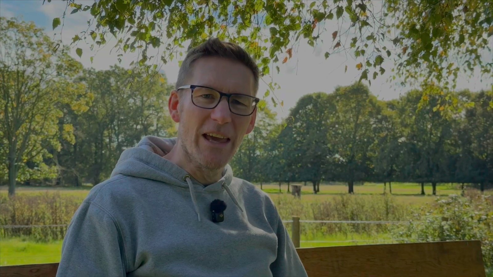 James talking to camera on a bench in the park